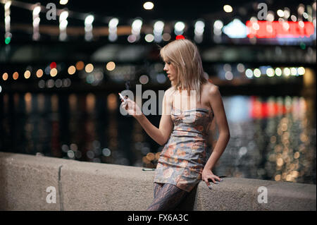 Caucasian woman smoking cigarette on urban bridge Stock Photo