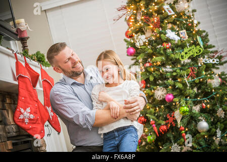 Caucasian father and daughter hugging near Christmas tree Stock Photo