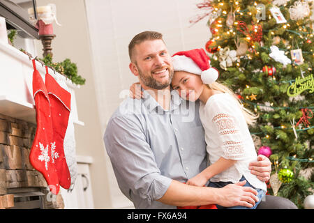 Caucasian father and daughter hugging near Christmas tree Stock Photo