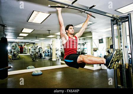 Man doing pull-ups in gymnasium Stock Photo
