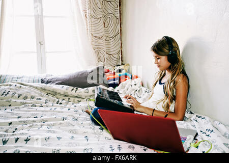 Native American girl recording music on bed Stock Photo