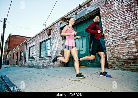 Caucasian couple jogging on sidewalk Stock Photo