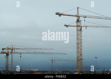 Five building cranes against an overcast sky Stock Photo