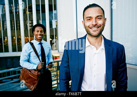 Businessmen smiling outside office building Stock Photo