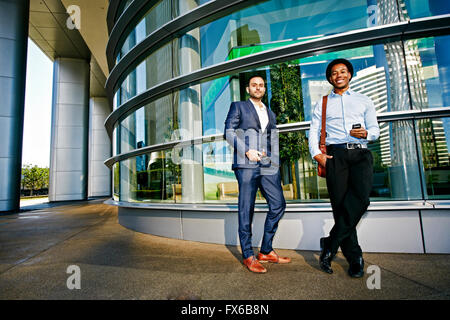 Businessmen smiling outside office building Stock Photo