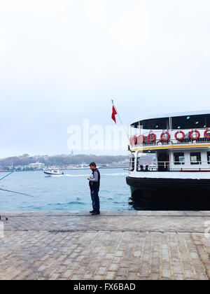 Fisherman and ferry in Karakoy station in Istanbul Stock Photo
