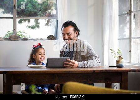 Hispanic father and daughter using digital tablet Stock Photo