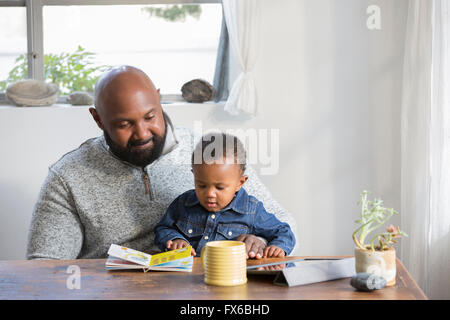 African American father and son reading book at table Stock Photo