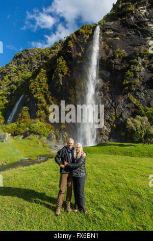 Caucasian couple hugging near remote waterfall Stock Photo