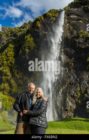 Caucasian couple hugging near remote waterfall Stock Photo
