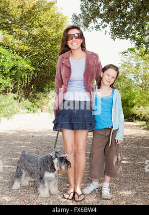 Caucasian mother and daughter walking dog on path Stock Photo