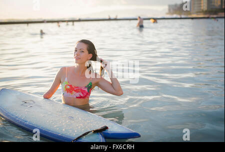 Mixed race amputee with surfboard in ocean Stock Photo