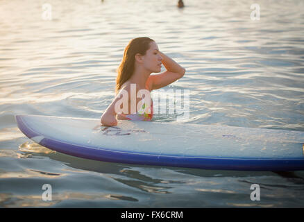 Mixed race amputee with surfboard in ocean Stock Photo