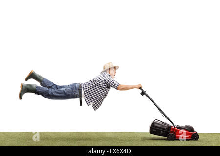 Studio shot of a mature man being pulled by a powerful lawn mower isolated on white background Stock Photo