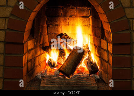 burning billets in fire-box of fireplace in country cottage Stock Photo