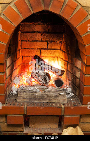 ash, coal and burning billets in fireplace in country cottage Stock Photo