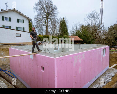 Prefabricated house, workers in setting up the basement walls on building site Stock Photo