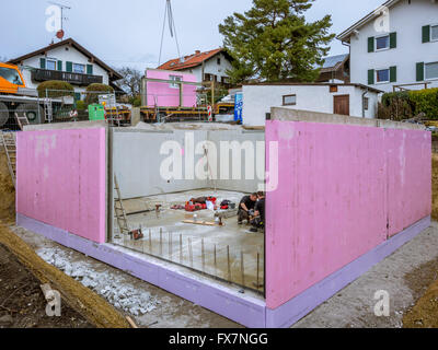 Prefabricated house, workers in setting up the basement walls on building site Stock Photo