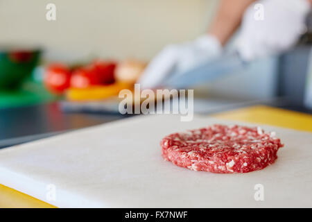 Raw hamburger patty on white board waiting to be seasoned Stock Photo