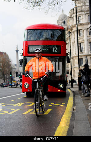 Man riding cow handlebar bicycle in front of red London bus Stock Photo