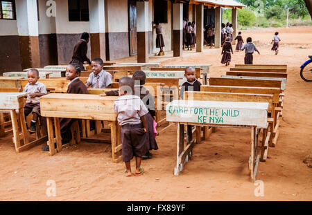 Children at charity desks set outdoors in a primary school near Voi in Southern Kenya Stock Photo