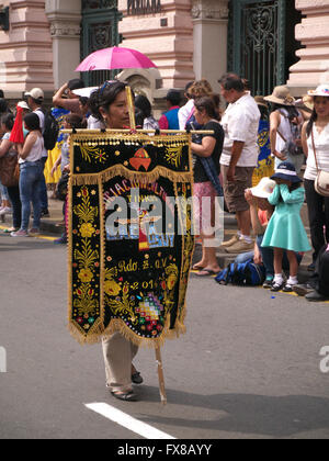 Standard bearer accompanying dancers and musicians in traditional Peruvian dress dancing in the street in Lima Stock Photo