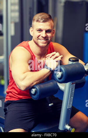 smiling man sitting on exercise bench in gym Stock Photo
