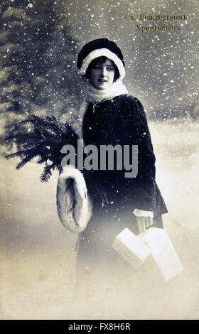 Postcard printed in Russia shows young woman on the background of snow-capped forest, circa 1915 Stock Photo
