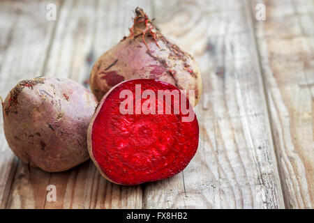 Dirty beetroots on rustic wooden background taken out of ground. One is sliced in half. Copy space Stock Photo