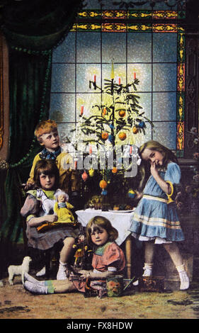 Greeting postcard printed in the Germany shows childrens near Christmas tree, circa 1914 Stock Photo