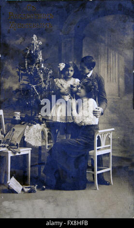 RUSSIA - CIRCA 1908: Postcard printed in Russia shows Parents with children near Christmas tree Stock Photo