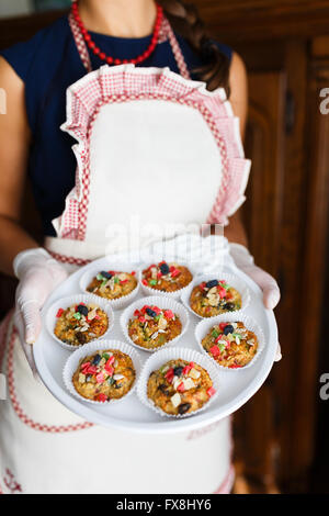 Young woman holding a tray with cupcakes at the kitchen Stock Photo