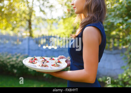 Young woman holding a tray with cupcakes in the garden Stock Photo