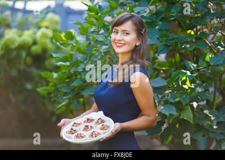 Young woman holding a tray with cupcakes in the garden Stock Photo