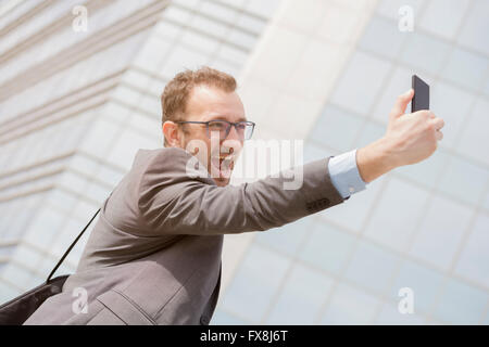 Young professional taking selfie in front of the blue glass business building Stock Photo