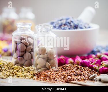 Bottles of natural tablets, healing herbs and mortar with dry lavender flowers, herbal medicine. Stock Photo