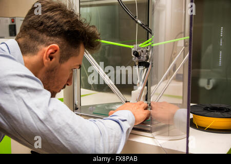 Brunet adult man working with 3D printer, observing the machine at work Stock Photo