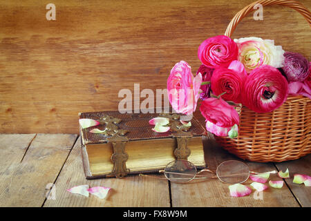 old book and glasses next to beautiful field flowers on wooden table. vintage filtered Stock Photo