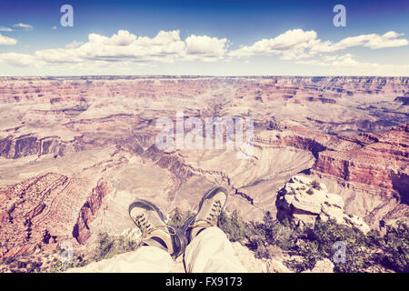 Vintage toned legs with old trekking shoes by the Grand Canyon cliff, adventure concept photo. Stock Photo
