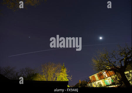 Wimbledon, London, UK. 12th April, 2016. The International Space Station tracks across the sky above London from W to SSE at 9:15pm for a period of 3 minutes at a speed of approx. 17,000mph, shining brightly as it passes under the moon (right) and planet Jupiter (left) in clear night skies. Credit:  Malcolm Park editorial/Alamy Live News. Stock Photo