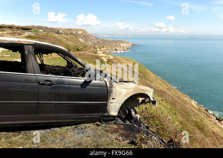 Burnt out car on cliff edge at Portland, Dorset, UK Stock Photo