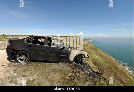 Burnt out car on cliff edge at Portland, Dorset, UK Stock Photo