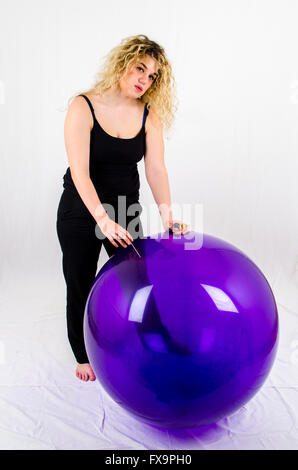 Young woman with a huge balloon and a needle Stock Photo