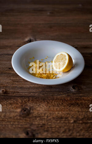 Half of lemon and grated lemon zest on a white plate Stock Photo