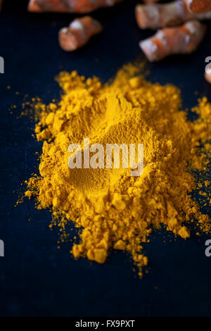 Ground yellow turmeric powder on the black surface Stock Photo