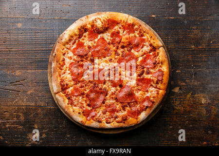 Heart shape sliced Pepperoni Pizza on wooden background Stock Photo