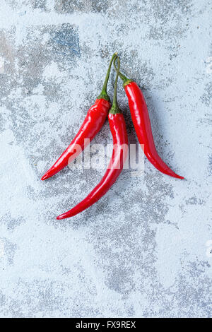 Red hot chili peppers over white textured background. With copy space. Top view. Stock Photo