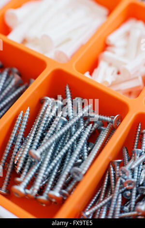 Screws and dowels on an orange box. Stock Photo