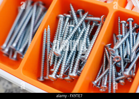 Screws and dowels on an orange box. Stock Photo