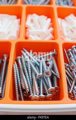 Screws and dowels on an orange box. Stock Photo